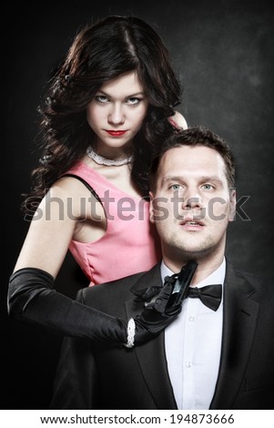 Detective theme. Retro style attractive couple, rich gangster and charming woman sexy detective spy with gun on black background