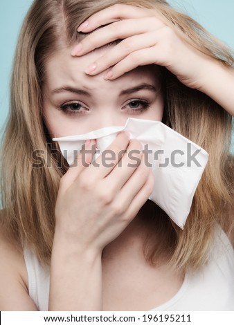 Flu cold or allergy symptom. Sick woman girl with fever sneezing in tissue on blue. Health care.