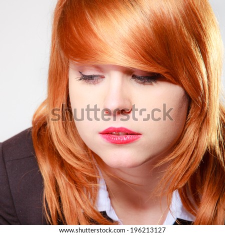 Portrait of sad unhappy businesswoman. Closeup of face redhaired girl on grey gray. Stress in work. Studio shot.