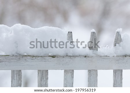 Old white wooden wood fence covered with fresh snow on winter season. Seasonal specific.