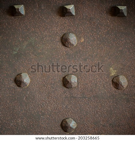 Brown grunge metal plate or armour texture with rivets as background. Square format