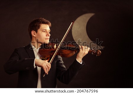 Art and artist. Young elegant in love man violinist fiddler playing violin at moon night. Classical music. Studio shot.