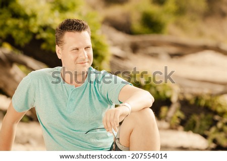 Happiness summer vacation and people concept. Fashion portrait handsome man on the beach, guy sitting on tree