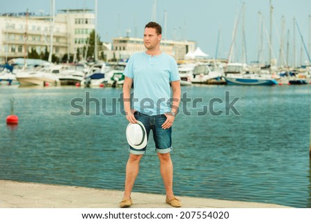 Travel summer vacation and people concept. Fashion portrait of handsome man on pier against white yachts in port