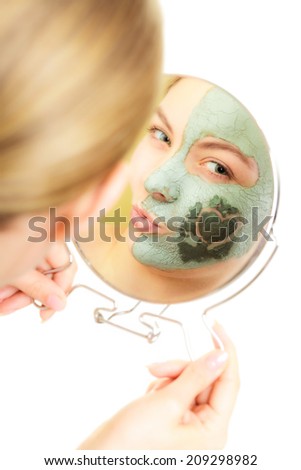 Skin care. Woman in clay mud mask on face with heart on cheek. Girl looking in the mirror and blowing a kiss isolated on white. Beauty treatment.