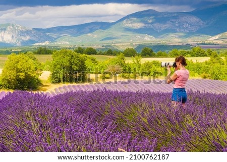 Mature tourist woman with camera taking travel photo from Provence landscape with purple lavender fields. Puimoisson region, Plateau Valensole, Alpes de Haute Provence in France Stok fotoğraf © 