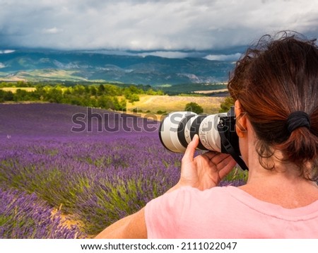 Mature tourist woman with camera taking travel photo from Provence landscape with purple lavender fields. Puimoisson region, Plateau Valensole, Alpes de Haute Provence in France Stok fotoğraf © 