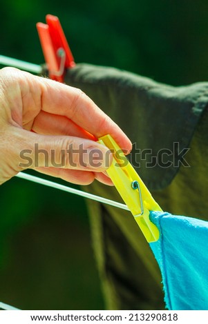 Housework. Woman hand hanging clean wet laundry to dry on the rope clothes line outdoor.