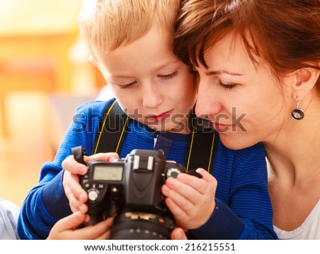 Happy childhood. Mother and her son boy child playing with camera taking picture at home. Real photo