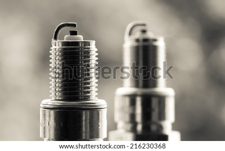Auto service. Two new car spark plugs as spare part of auto transportation on blurry gray background.