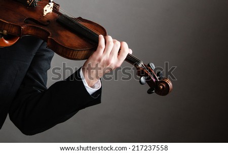 Art and artist. Closeup of male hands. Man violinist fiddler holding violin on dark gray. Classical music. Studio shot.