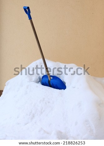 blue snow shovel standing up in deep snow, winter scenery
