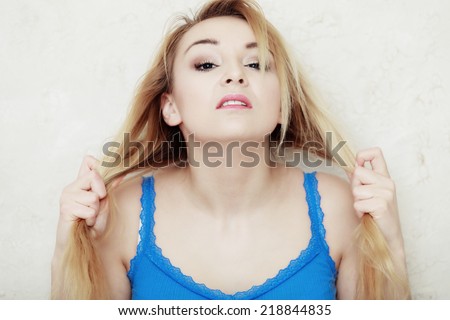 Hair problem. Blond woman teenage girl showing her damaged dry hair. Indoor.