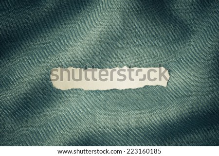 Piece scrap of white torn or ripped paper banner, blank copy space for text message on blue fabric textile material background