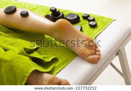 Day-spa. Close-up of female legs. Young woman relaxing in healthy spa salon. Girl having hot stone massage. Indoor.