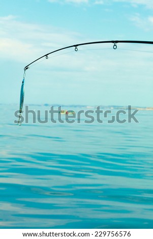 Sport and recreation. Fishing bait - rod with wobbler against the blue sea water surface