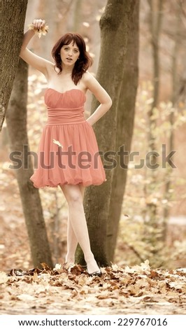 Full length fashionable young woman in red dress outdoor relaxing walking in park vintage photo sepia tone