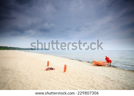 Beach life-saving. Lifeguard rescue equipment orange preserver tool and boat, red plastic buoyancy aid in the sand