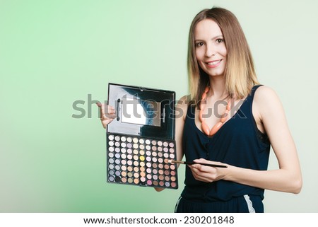 Cosmetic beauty procedures and makeover concept. Woman holds makeup professional palette and brush. Make-up applying with accessories tools. Green background