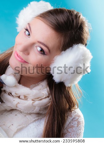 Winter fashion ear protection. Portrait positive teen girl in warm clothes. Happy woman in white earmuffs on blue