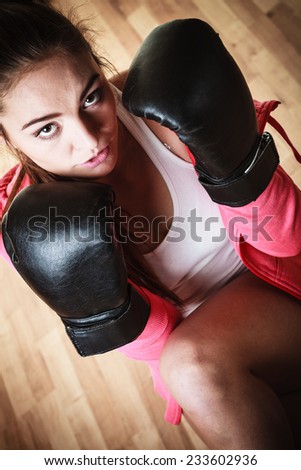 Martial arts or self defence concept. Sport boxer woman in black gloves. Fitness girl training kick boxing.