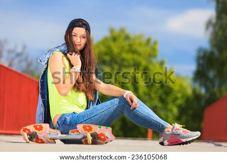Summer sport and active lifestyle. Cool teenage girl skater sitting with skateboard on the street. Outdoor.