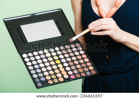 Cosmetic beauty procedures and makeover concept. Woman holds makeup professional palette and brush. Make-up applying with accessories tools. Green background
