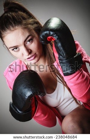 Martial arts or self defense concept. Sport boxer woman in black gloves. Fitness girl training kick boxing.