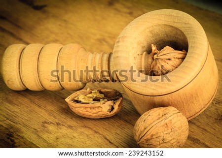 Healthy food full of omega-3 fatty acids, organic nutrition. Closeup walnut and nutcracker on rustic old wooden table