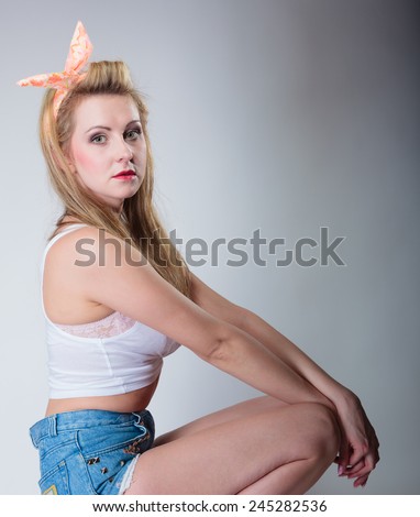 pin up beautiful blonde fashion girl in hairband retro styling, studio shot gray background