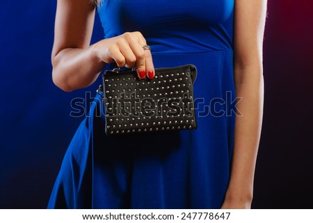 Fashion elegant evening outfit. Close up female hand holding black rivet leather handbag bag