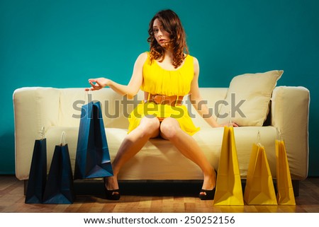 Buying retail sale concept. Fashionable girl yellow dress high heels sitting on couch with shopping bags