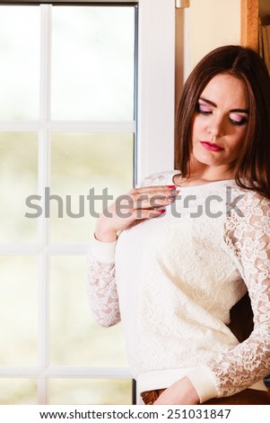 People and solitude concept. Beautiful alone serious woman long hair looking dreaming through window indoor