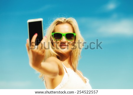 Technology internet tourism vacation concept - happy woman teen girl taking self picture with smartphone camera on beach
