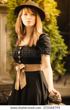 Portrait of young woman outdoors. Retro style fashion girl in black hat and dress on street of the old town european city Gdansk Danzig Poland