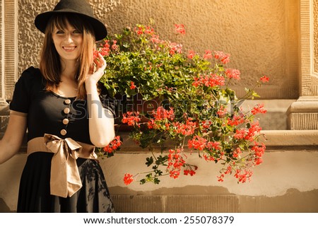 Portrait of young romantic woman outdoors. Retro styling fashion girl in black hat and dress on street of the old town city Gdansk Danzig Poland
