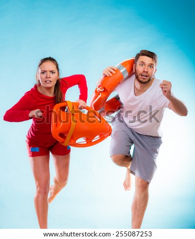Accident prevention and water rescue. man and woman lifeguard couple on duty running with with life belt lifesaver equipment on blue