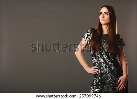 Event or celebration. Elegant woman in evening sequin dress on gray background. Studio shot.