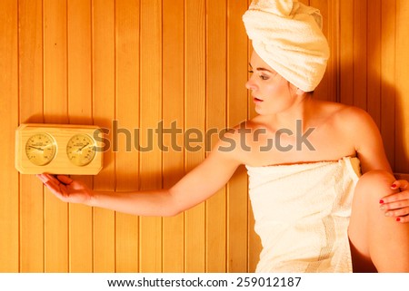Beauty health spa concept. Woman relaxing in sauna interior looking on equipment thermometer and hygrometer.