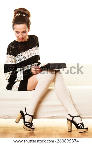 Technology internet concept. Fashion trendy woman sitting with tablet on white couch at home