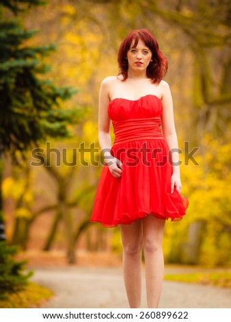 Full length fashionable elegant young woman in red dress outdoor relaxing walking in autumn park