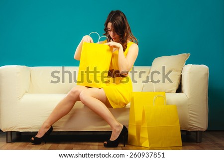 Buying retail sale concept. Fashionable girl yellow dress high heels sitting on couch with shopping bags