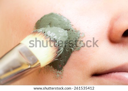 Skin care. Closeup of woman applying with brush clay mud mask on face. Girl taking care of dry complexion. Beauty treatment.