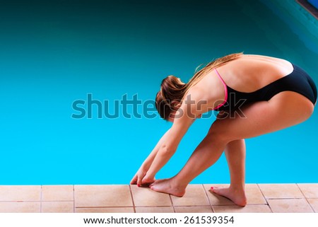 Sport active lifestyle. Sporty woman female swimmer muscular fit body preparing to jumping and diving into swimming pool sideview