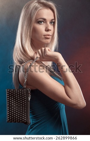 Fashion elegant evening outfit. Stylish woman fashionable blonde girl holding black rivet leather handbag bag in night club dancing.