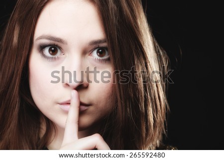 Secret woman finger on lips. Teen girl showing hand silence sign, saying hush be quiet on black
