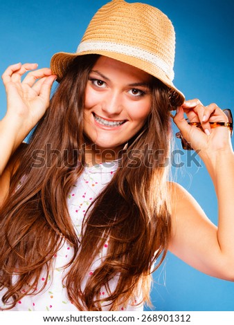 Youth and vacation concept. Happy teen girl in summer clothes and straw hat. Portrait of smiling beauty woman tourist on blue.