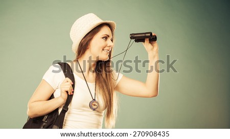 Summer holidays and tourism concept. Lovely tourist woman with backpack compass looking through binoculars filtered photo