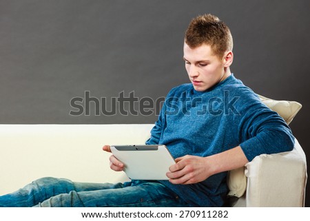 Modern technology leisure and lifestyle concept. Young handsome man with pc computer tablet relaxing on couch at home