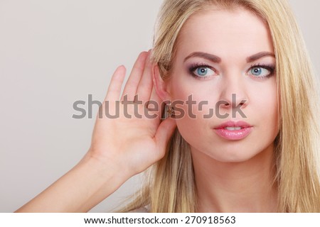 Female hand to ear listening on gray. Gossip girl with palm behind ear spying. Closeup young business woman listening secret.